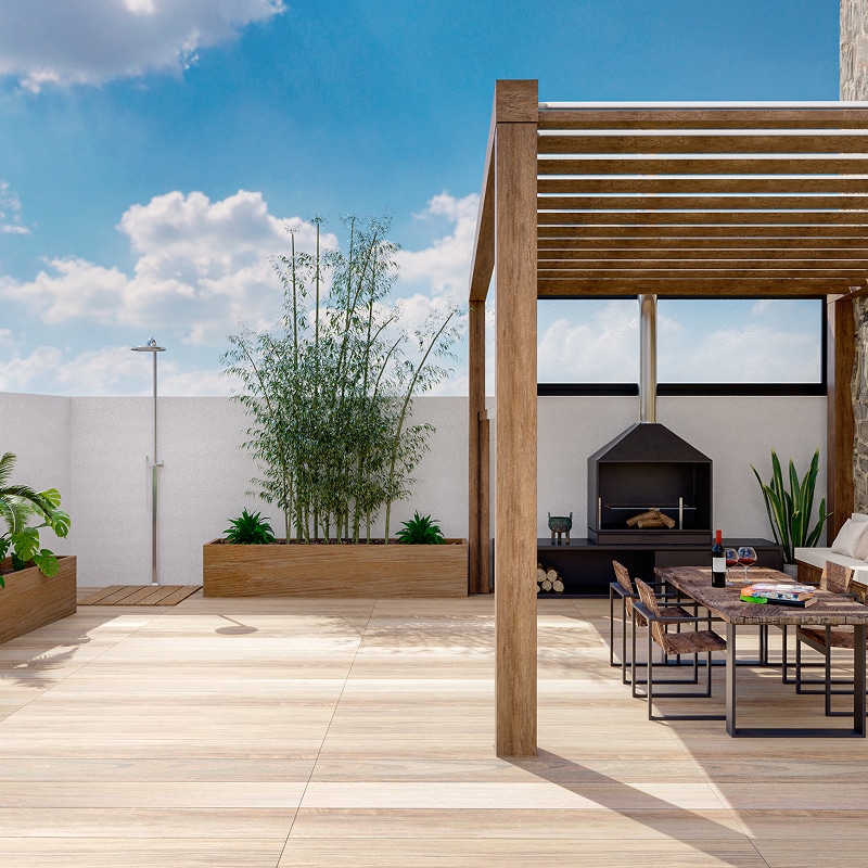 Terrasse aménagée avec pergola en bois, coin barbecue, table à manger, bambous en pot et douche extérieure.